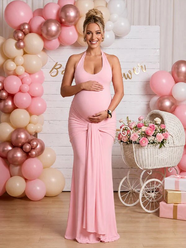 Pink maternity maxi dress with halter neck, ruched bowknot draped backless design, and bodycon silhouette, designed for baby shower.