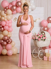 Pink maternity maxi dress with halter neck, ruched bowknot draped backless design, and bodycon silhouette, designed for baby shower.