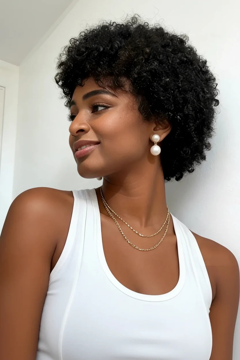 Woman with styled hair wearing pearl earrings and gold necklaces against a white background, Obroi