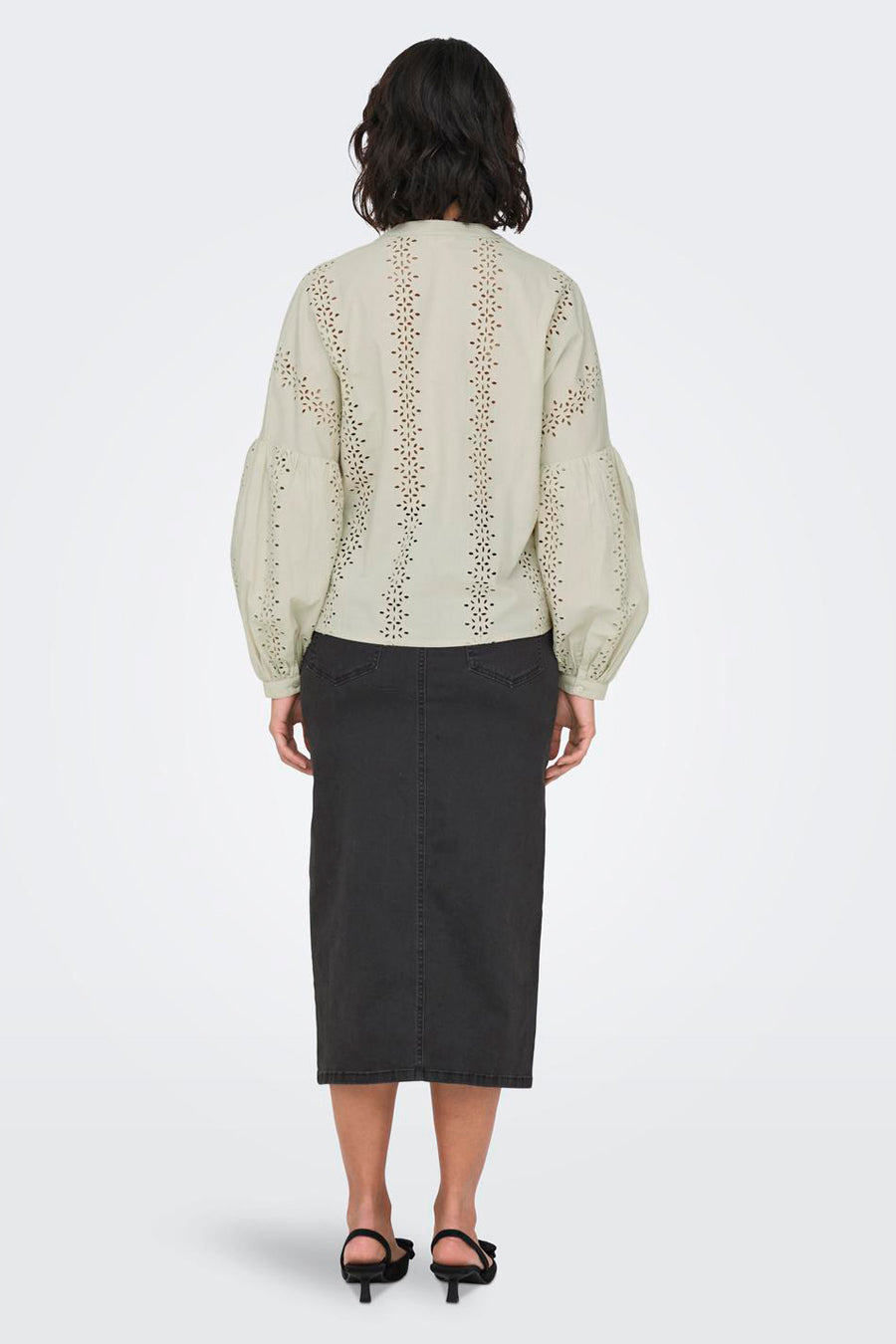 Ecru blouse met lange mouwen van ONLY, met opengewerkte details en gepofte mouwen, gecombineerd met een zwarte rok.

